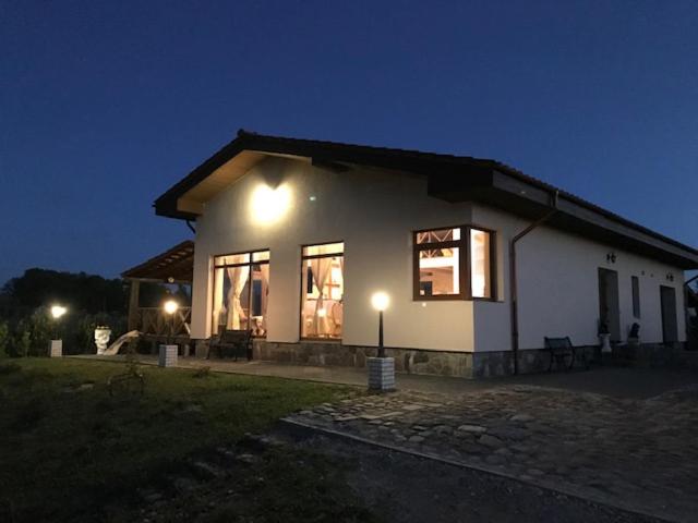 ein kleines weißes Haus mit Lichtern in der Nacht in der Unterkunft Sodyba Gintaras in Priekulė