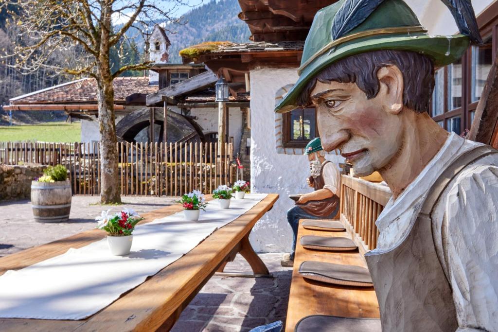 une statue d'un homme assis à une table dans l'établissement Appartements Gasthof Schleifmühle Unterammergau, à Unterammergau