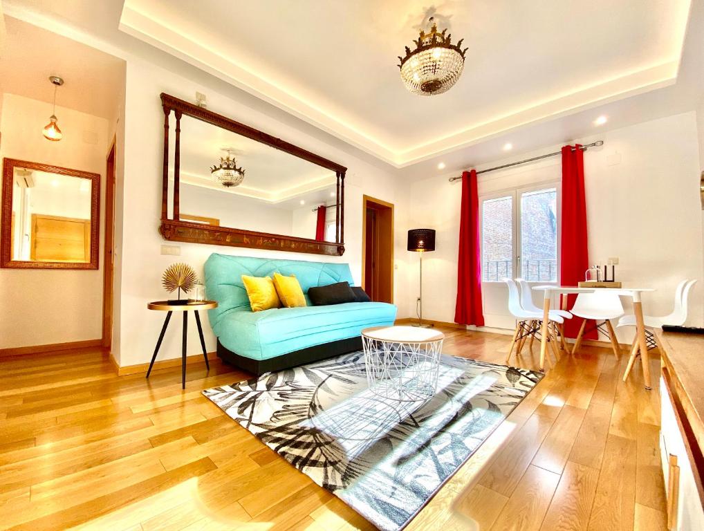 uma sala de estar com um sofá azul e um espelho em Charming Huertas II em Madri
