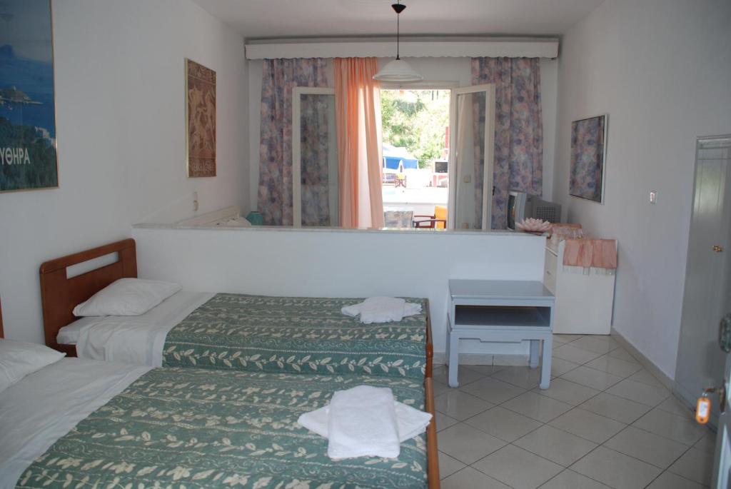 a bedroom with two beds and a desk and a mirror at Alessandro in Sidari