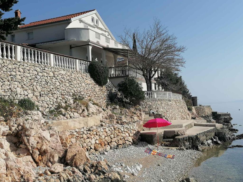 a house on top of a rock wall with a pink umbrella at One-Bedroom Apartment in Baric Draga II in Barić Draga