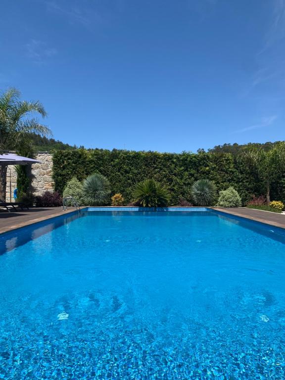 a large swimming pool with blue water at Quinta de Santa Ana, em Vizela in Infias