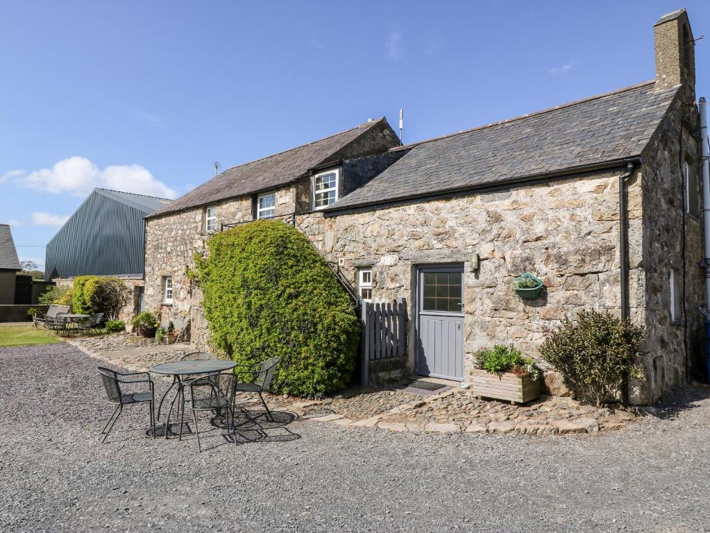 a stone building with a table and chairs in front of it at Stable 1 in Llanbedrog