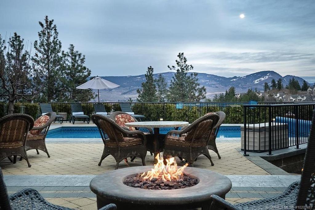 een vuurplaats met stoelen en een tafel naast een zwembad bij Under the Tree - Bed & Breakfast in Kelowna