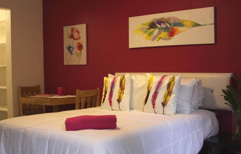 uma cama com lençóis brancos e almofadas num quarto em Super Precio em Guatemala
