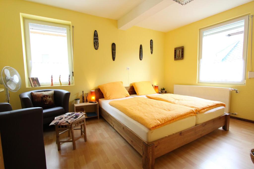 1 dormitorio con 1 cama, 1 silla y 2 ventanas en B&B Briedel, en Briedel