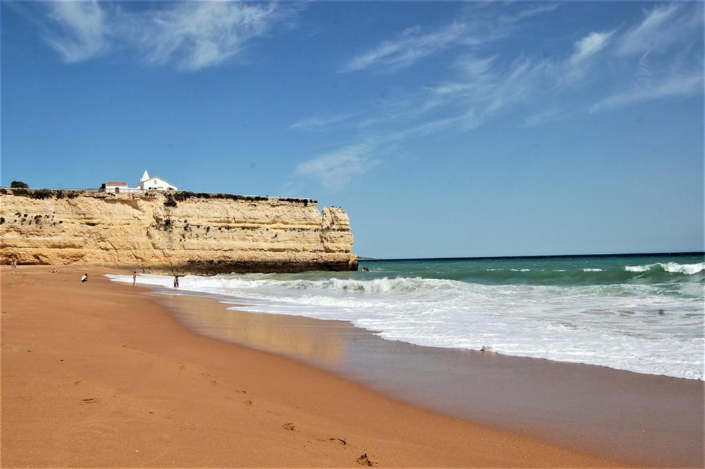 a beach with a cliff and the ocean with waves at Favorite at Senhora da Rocha in Porches