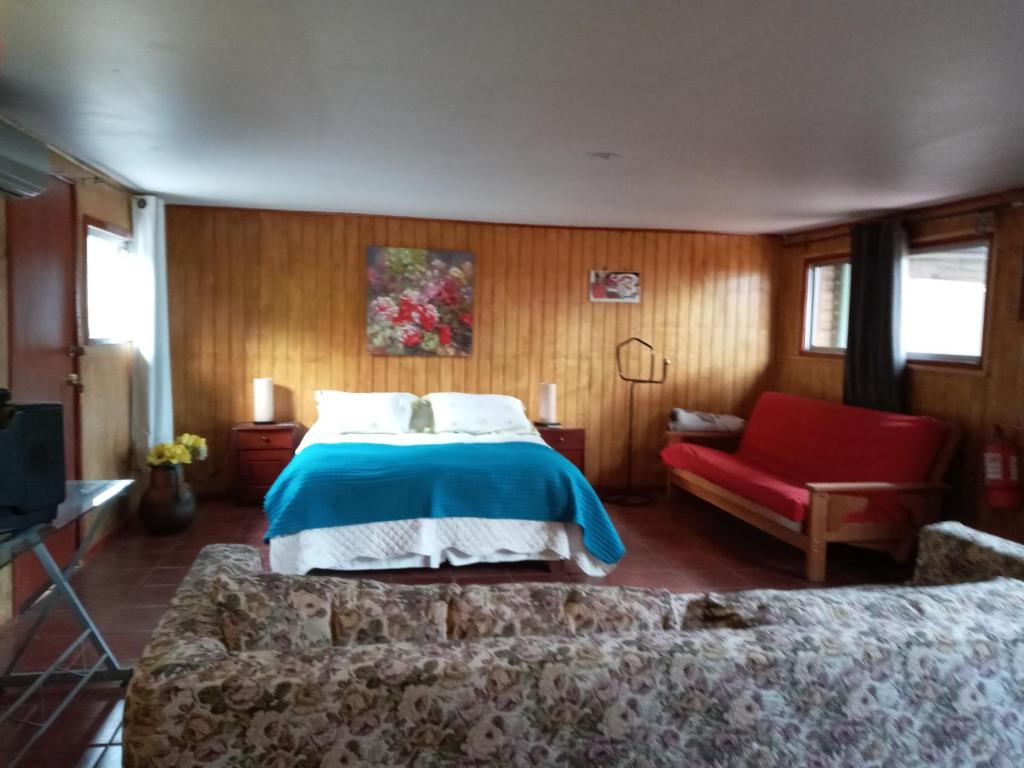 a bedroom with a bed and a red chair at Cabaña Cerezo in Guayacán