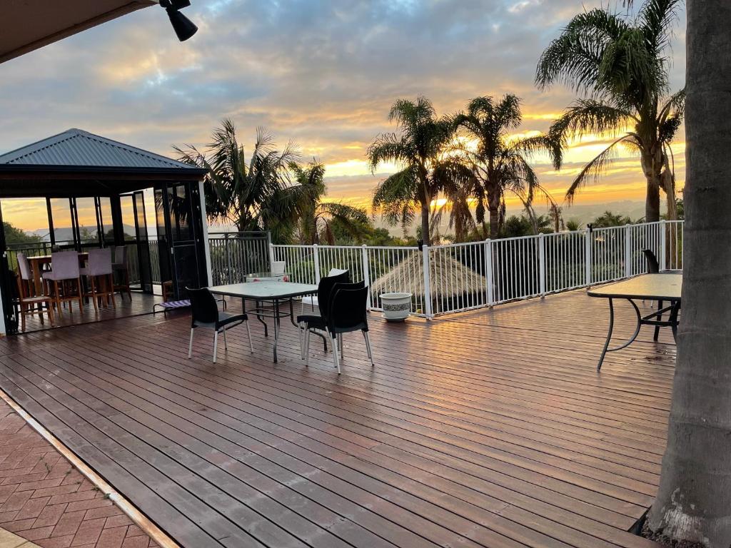 una terraza con mesas, sillas y palmeras en Lakeside Retreat, en Perth