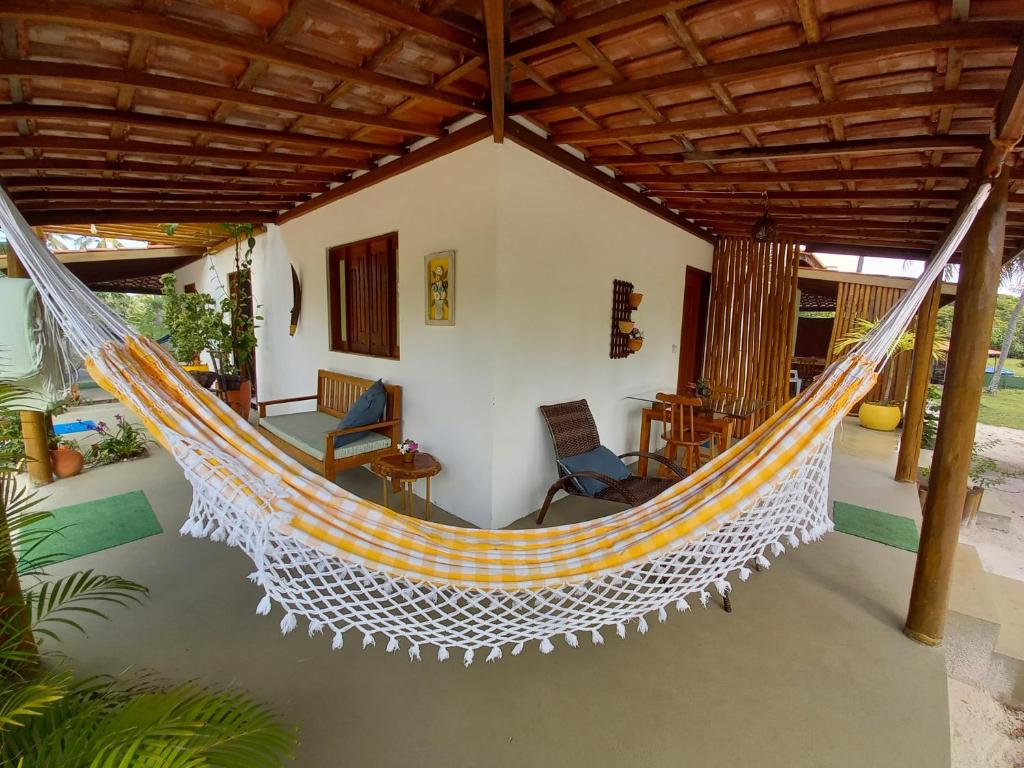 a hammock on the porch of a house at Recanto Verde - Praia de Santo Antônio in Diogo