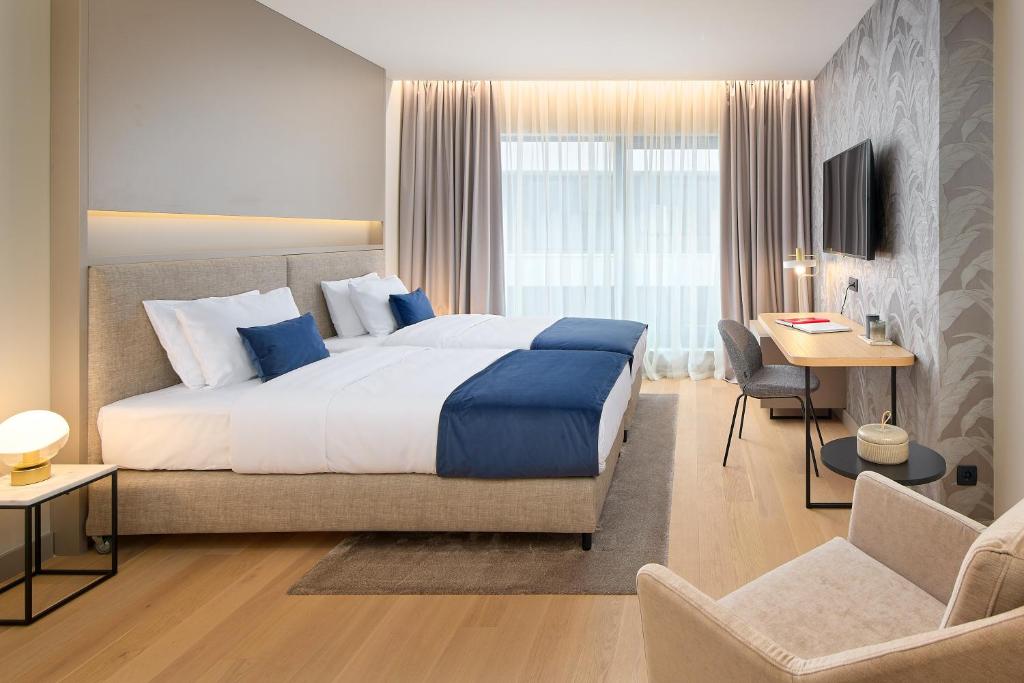 a hotel room with a large bed and a desk at Boutique Hotel Porto in Dubrovnik