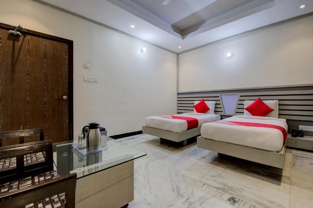 a hotel room with two beds and a desk at OYO 1545 Hotel Shivani International in Ahmedabad