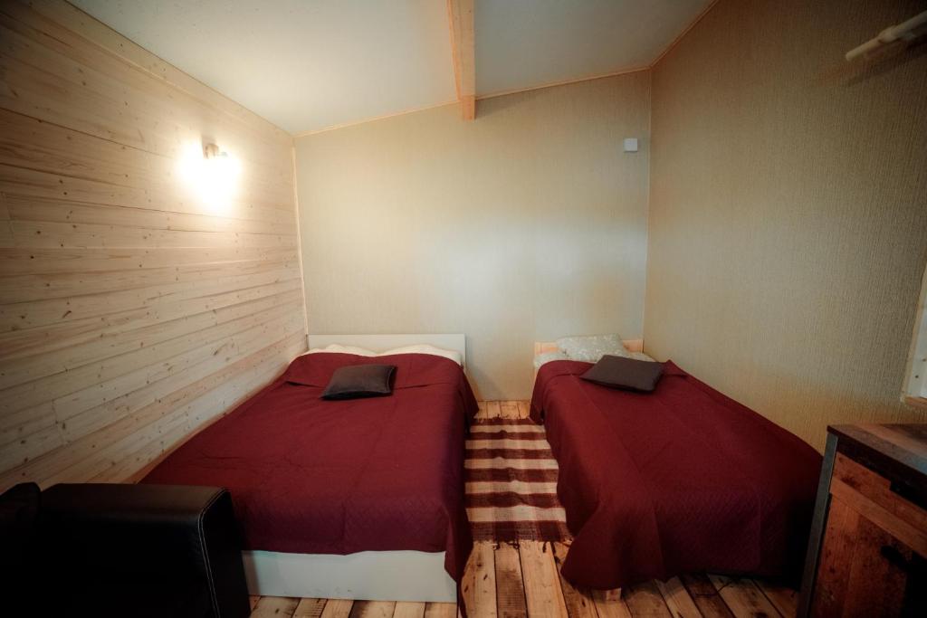 two beds in a small room with wooden floors at Rijnieki upes namiņš in Koknese