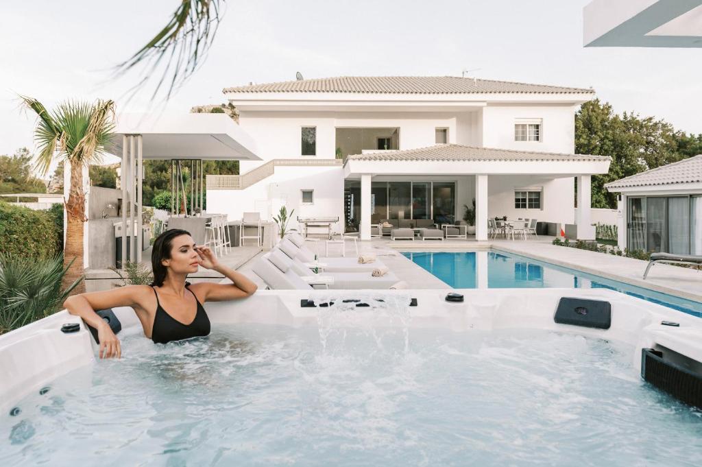 a woman sitting in a swimming pool next to a house at M Mansion in Pefki Rhodes