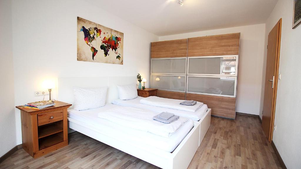 a bedroom with a white bed and a wooden night stand at Generous & bright flat - private Parking, daylight bathroom - by homekeepers in Zell am Main