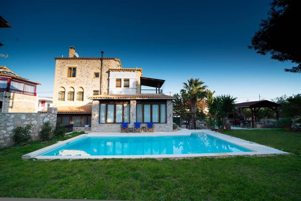 a house with a swimming pool in front of a house at Stone Villa Lagonisi in Lagonissi