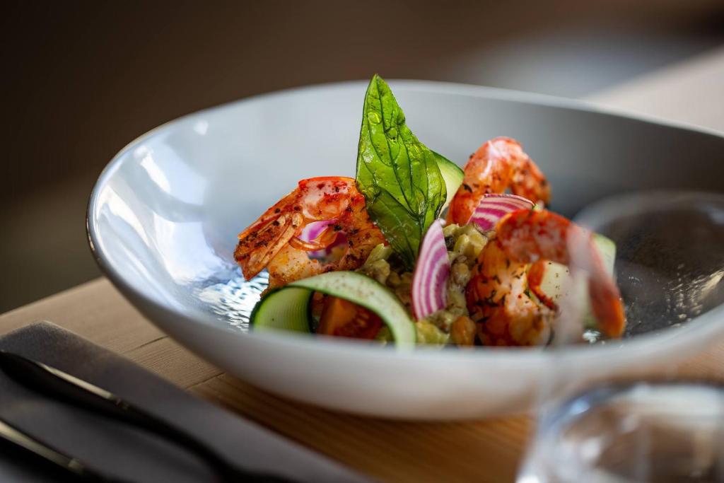 a bowl of food with shrimp and vegetables on a table at Hôtel Restaurant Le Monêtier in Le Monêtier-les-Bains