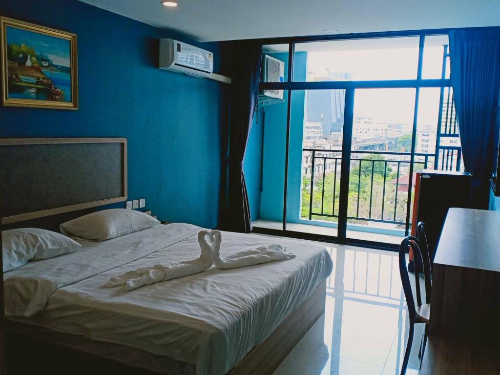 a bedroom with a bed with blue walls and a large window at @81Hotel in Bangkok