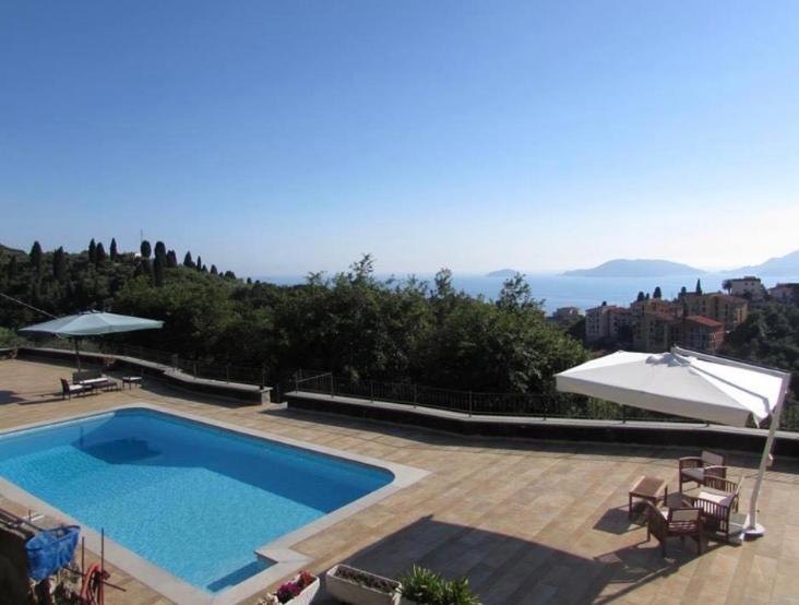 a swimming pool with an umbrella and some tables and chairs at Villa Antonini in Lerici