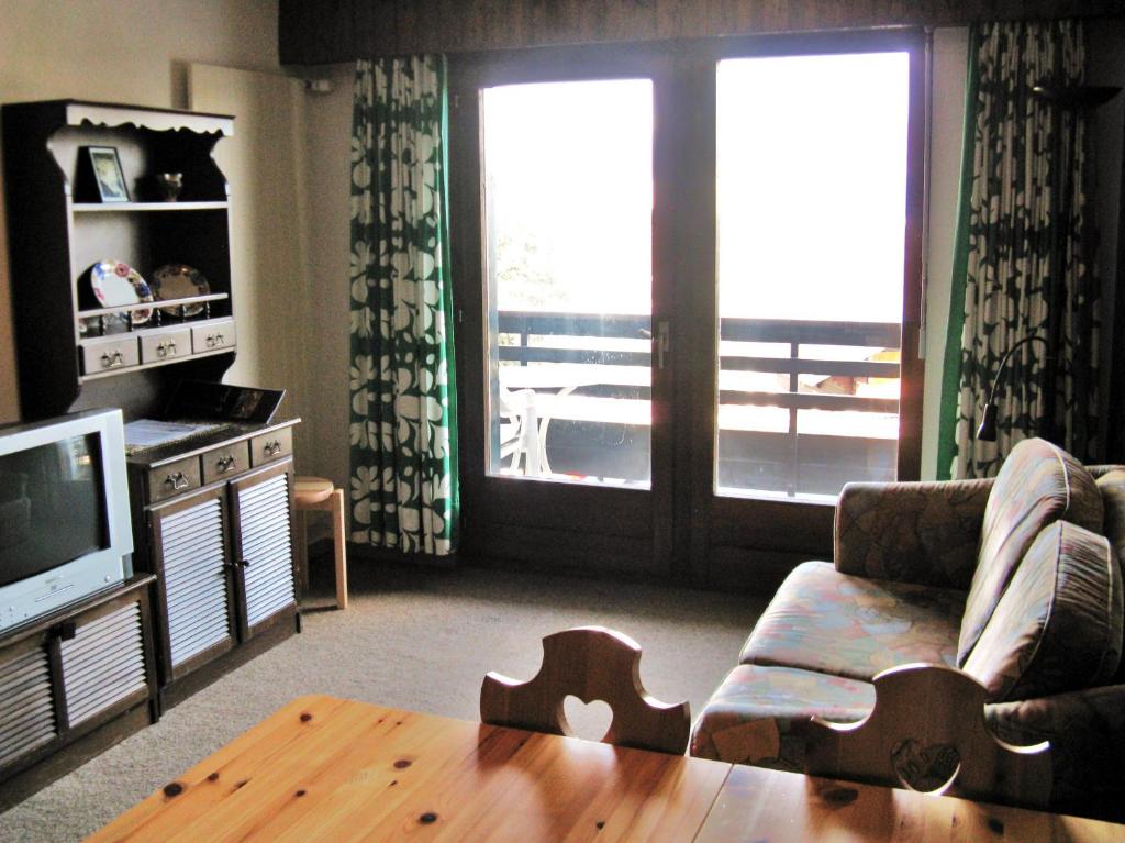Ramuge COSY & MOUNTAINS apartments في فييسوناز: غرفة معيشة مع أريكة وطاولة وتلفزيون