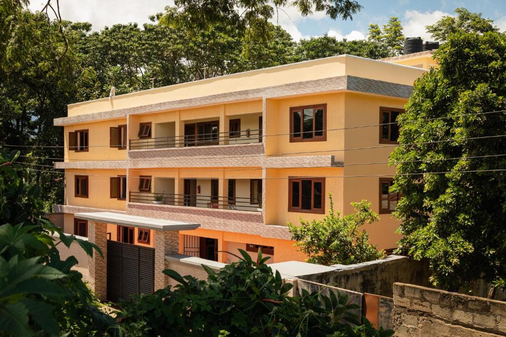 a yellow building with trees in front of it at Villa Viva Tanzania in Arusha