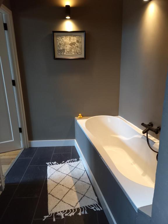 a bath tub in a bathroom with a picture on the wall at Vakantiehuis De Oude Bakkerij in Katwijk aan Zee