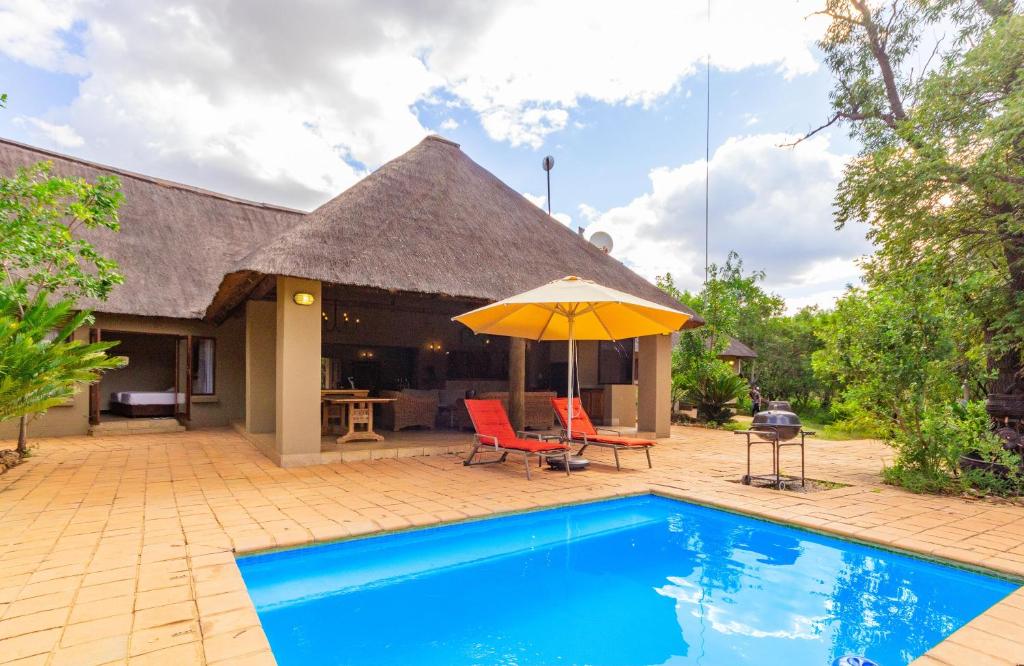 a house with a swimming pool and an umbrella at Zebula Golf Estate 77, Bela Bela in Bela-Bela