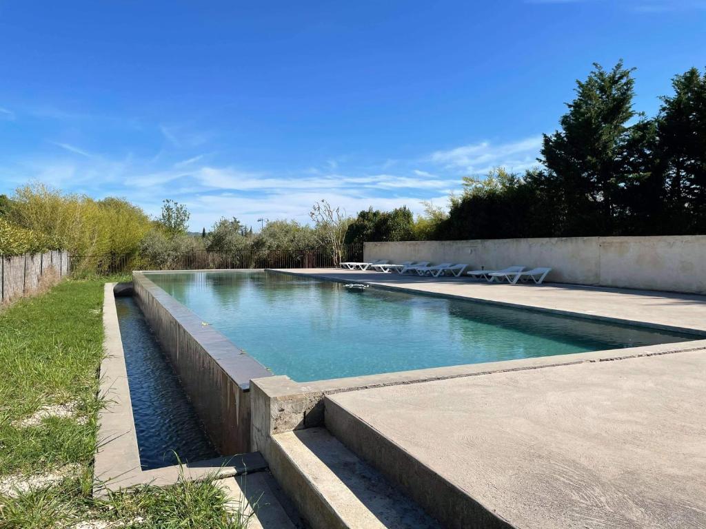 a swimming pool with blue water in a yard at Appartement de charme Sud Luberon classé 4 étoiles in Puyvert