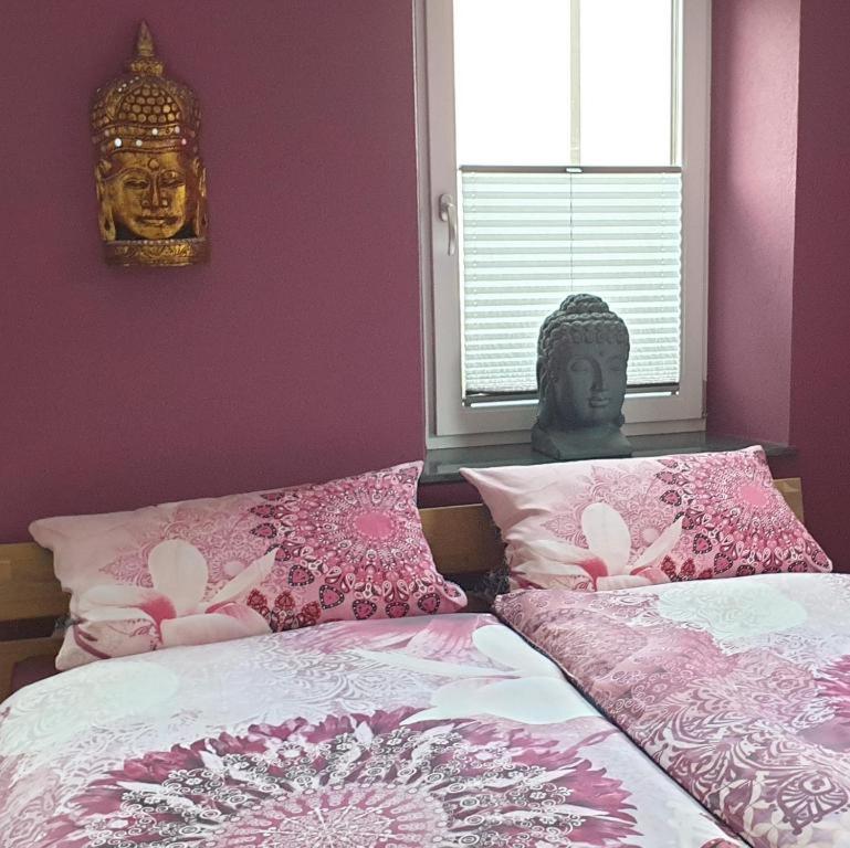 a bedroom with a bed with pink sheets and a statue at Schlafwelt - Thailand in Elsenfeld