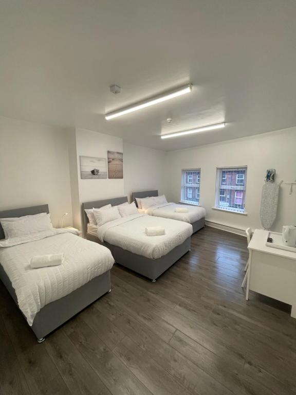 een kamer met 2 bedden en een bureau met een wastafel bij County serviced accommodation in Liverpool