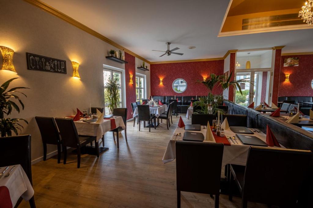 uma sala de jantar com mesas e cadeiras num restaurante em Check Inn Hotel Merseburg em Merseburg