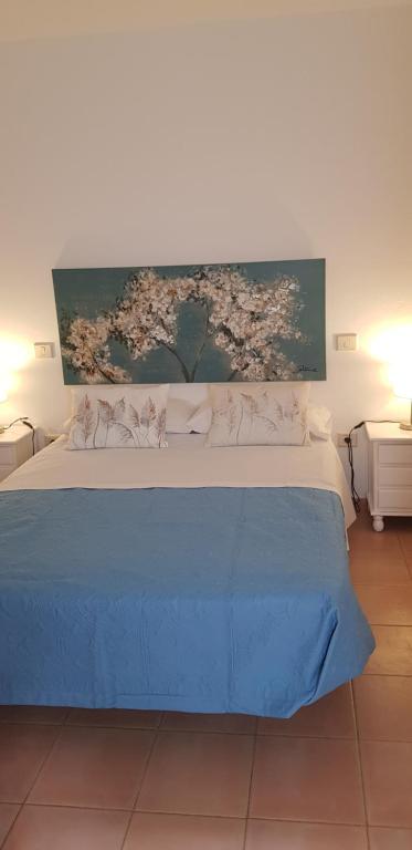Un dormitorio con una cama azul con una pintura en la pared en Centro Nuevo, en Corralejo