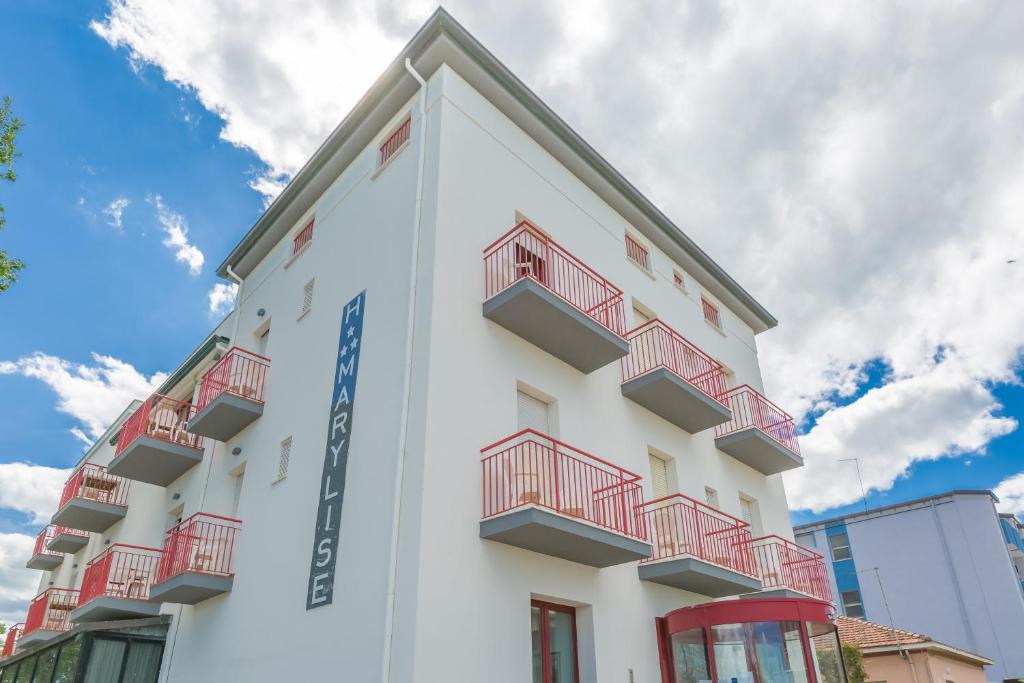 een wit gebouw met rode balkons erop bij Hotel Marylise in Rimini