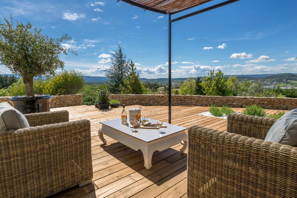 um pátio com uma mesa e cadeiras num deque de madeira em Villa Domitia Chambre d'Hôtes Luberon em Bonnieux