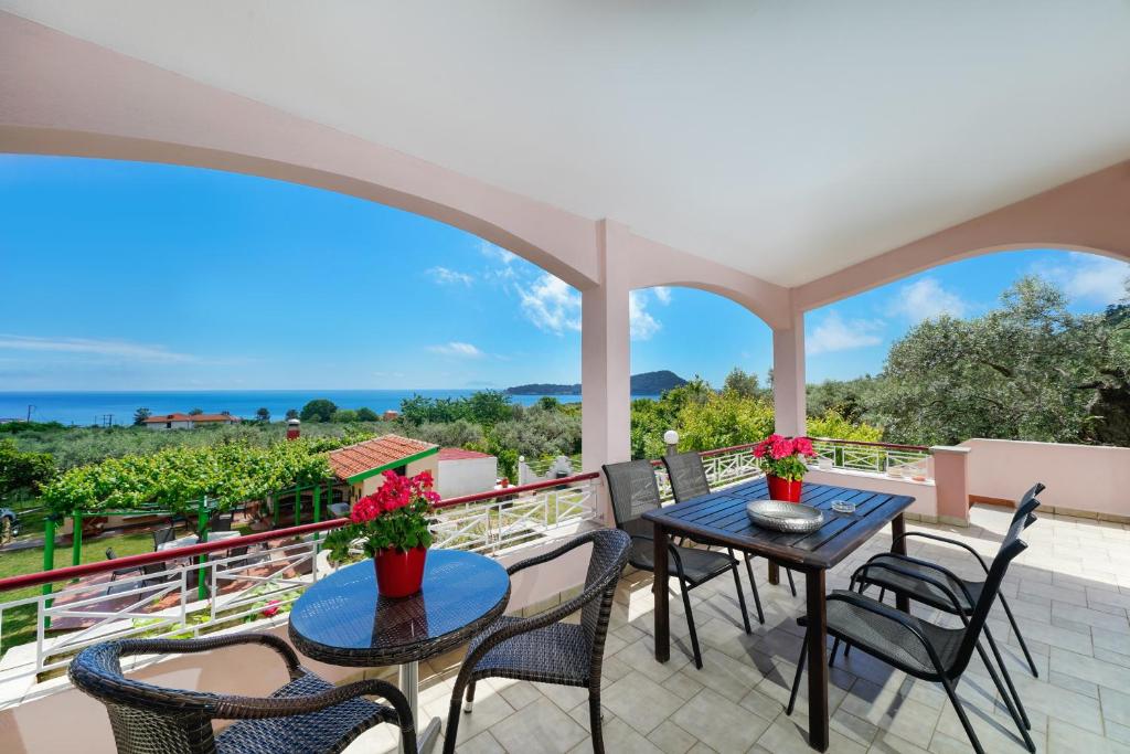 a balcony with tables and chairs and a view of the ocean at Villa Melina 2 in Kinira