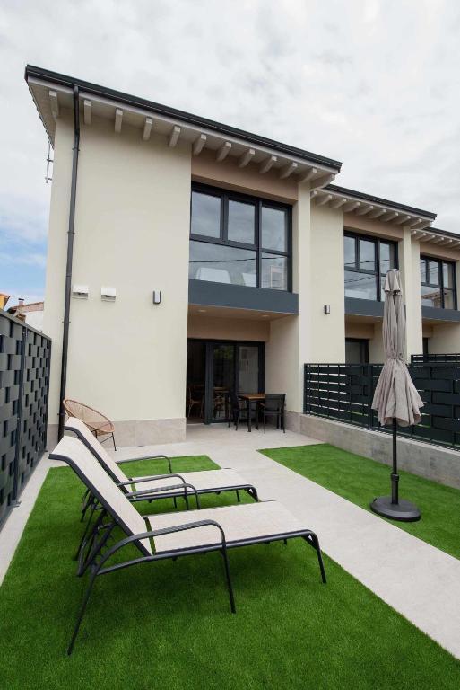 a patio with two benches and a house at ADOSADO-DUPLEX ADAPTADO zona de playa y montaña in Llanes