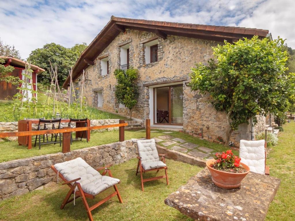 een stenen huis met een tuin met stoelen en een tafel bij Tranquilidad en la Reserva de Urdaibai in Canala