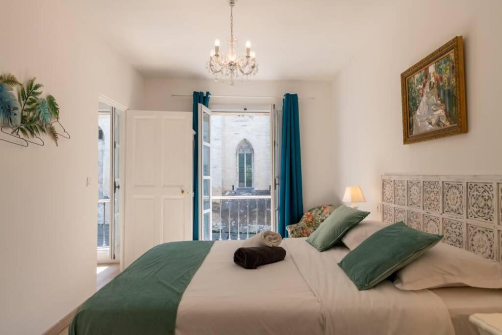 ein Schlafzimmer mit einem großen Bett mit einem Kronleuchter in der Unterkunft Bien d'exception en face du Palais des Papes in Avignon