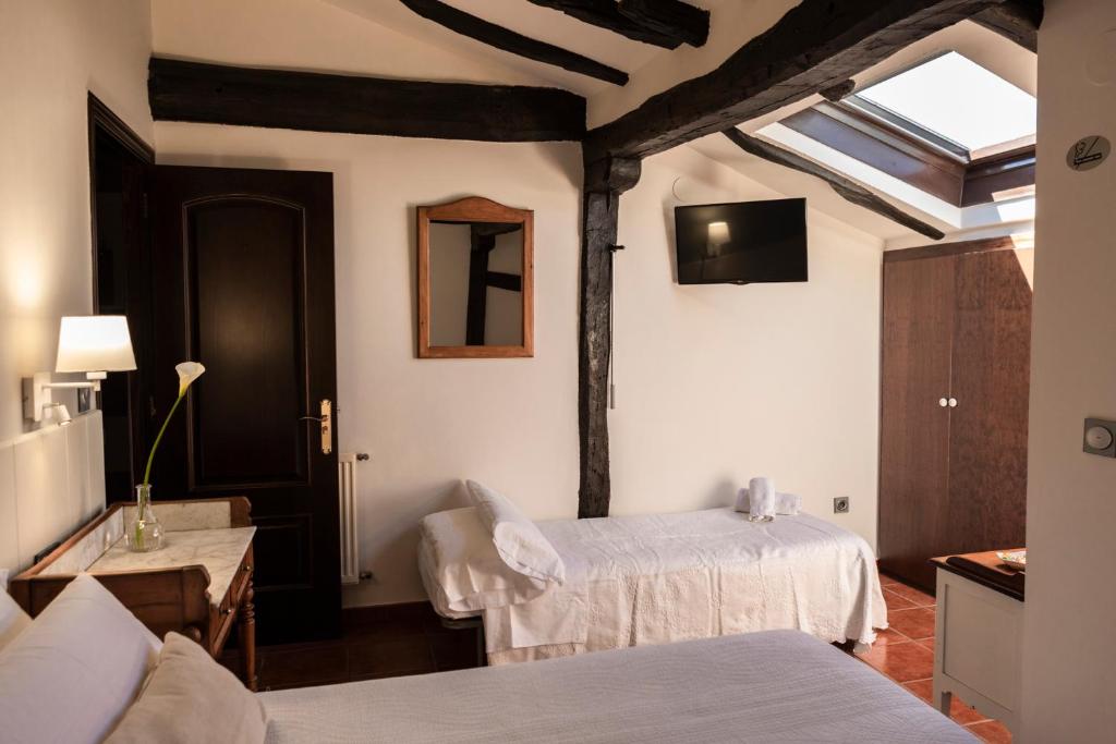 een kamer met 2 bedden en een tv aan de muur bij Agroturismo Montefrío in Urnieta