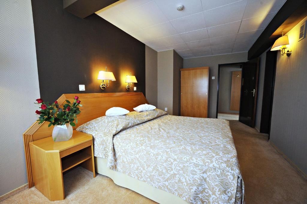 Un dormitorio con una cama y una mesa con flores. en Hotel Sport, en Bełchatów