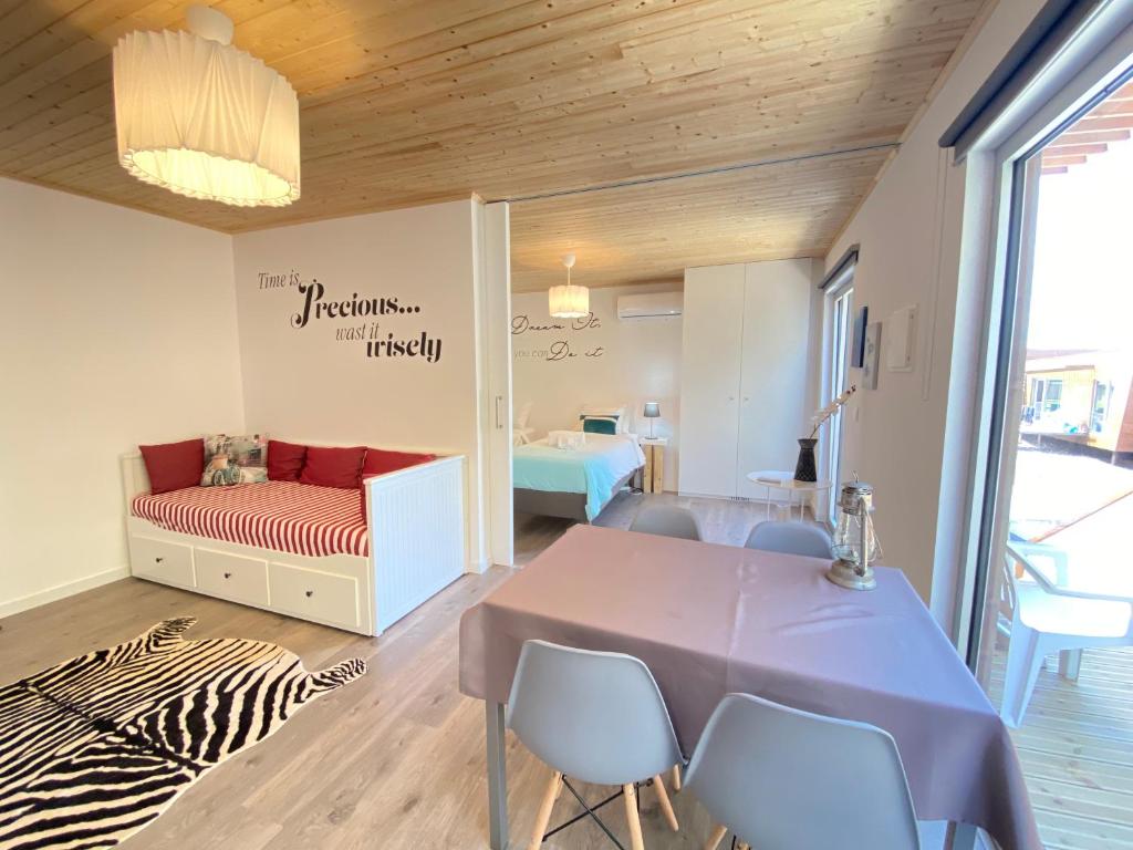 a room with a bed and a table and chairs at Golden Halcyon - Ericeira Villas in Ericeira