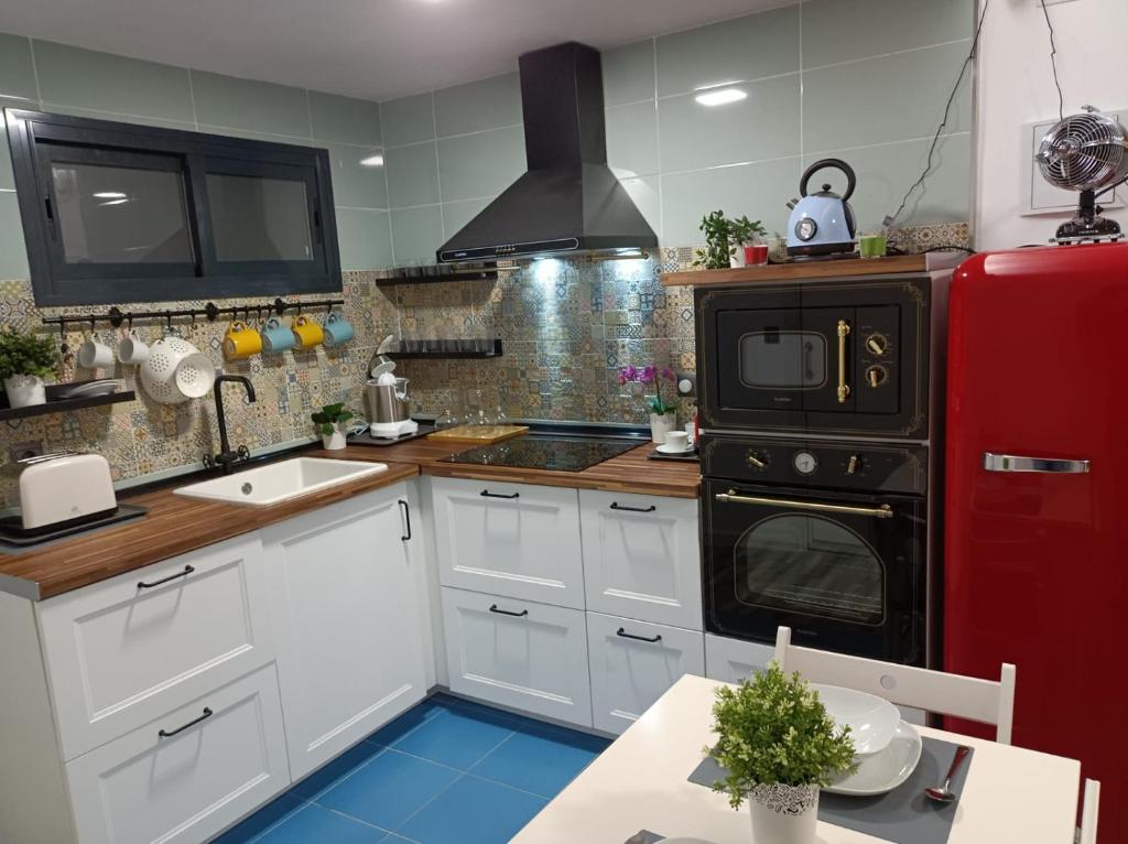 La cuisine est équipée de placards blancs et d'un réfrigérateur rouge. dans l'établissement Centro Torremolinos Apto 1 hab 1-4 personas WiFi Terraza, à Torremolinos
