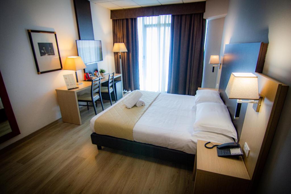 Pokój hotelowy z łóżkiem i biurkiem w obiekcie Tuscany Inn w Montecatini Terme