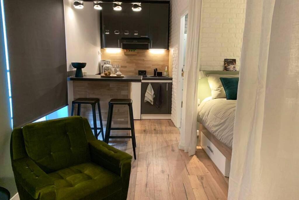 Il comprend une petite cuisine et une chambre avec un lit et une chaise. dans l'établissement Un petit air de Manhattan Coeur de ville Room 1, à Clermont-Ferrand
