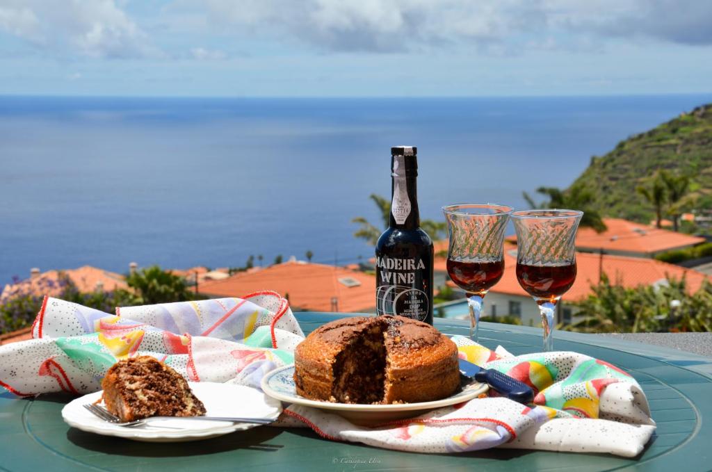 uma mesa com uma garrafa de vinho e um bolo e copos de vinho em Teixeira House em Arco da Calheta