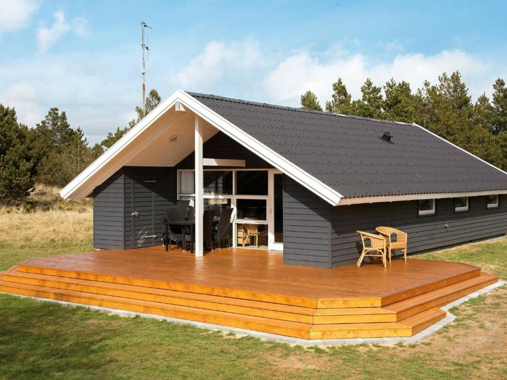 a black house with a wooden deck with a kitchen at 6 person holiday home in Bl vand in Blåvand