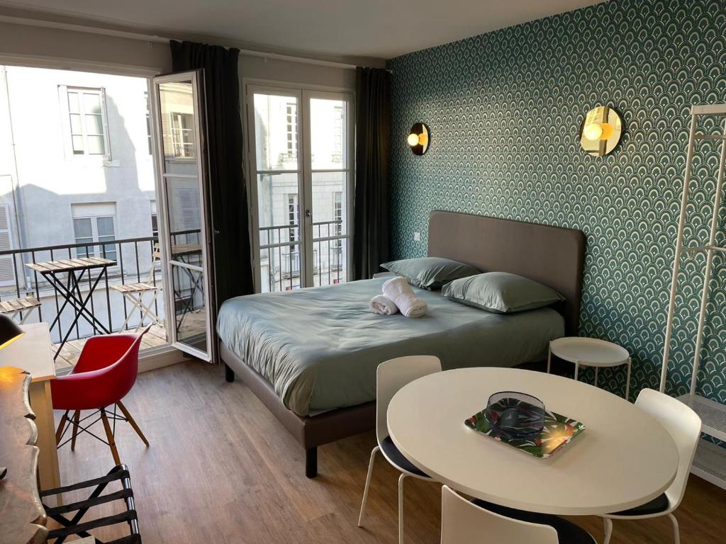 - une chambre avec un lit, une table et des chaises dans l'établissement Chaleureux studio * Neuf * Hypercentre * Wifi *, à Orléans