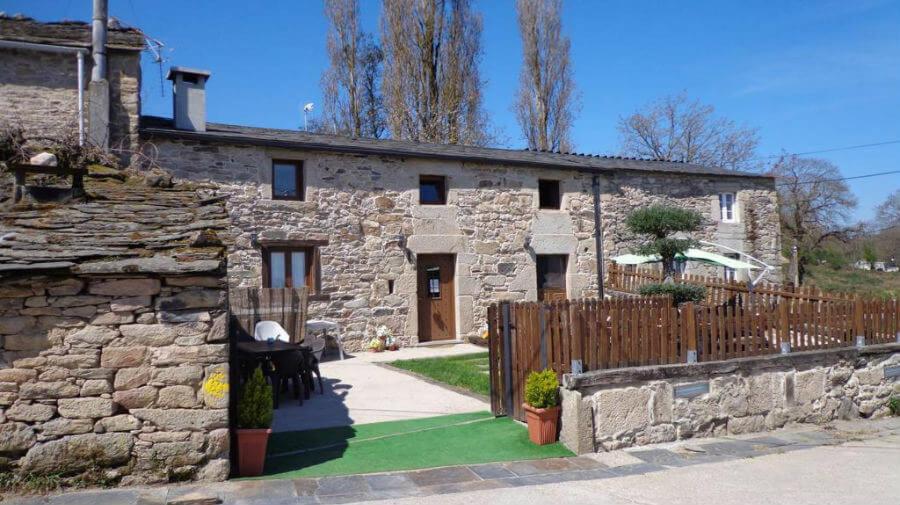 a stone house with a wooden fence in front of it at Casa Das Airas in Sarria