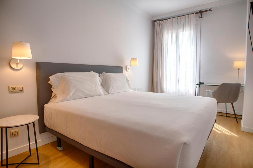 - une chambre avec un grand lit blanc et une chaise dans l'établissement Sercotel Tribuna Málaga, à Malaga