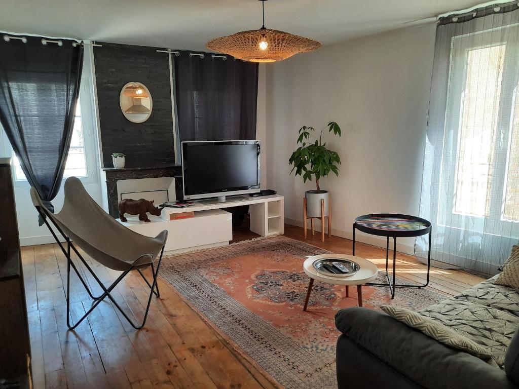 a living room with a couch and a tv at L'appartement du Pilori 1er étage in Saint-Jean-dʼAngély